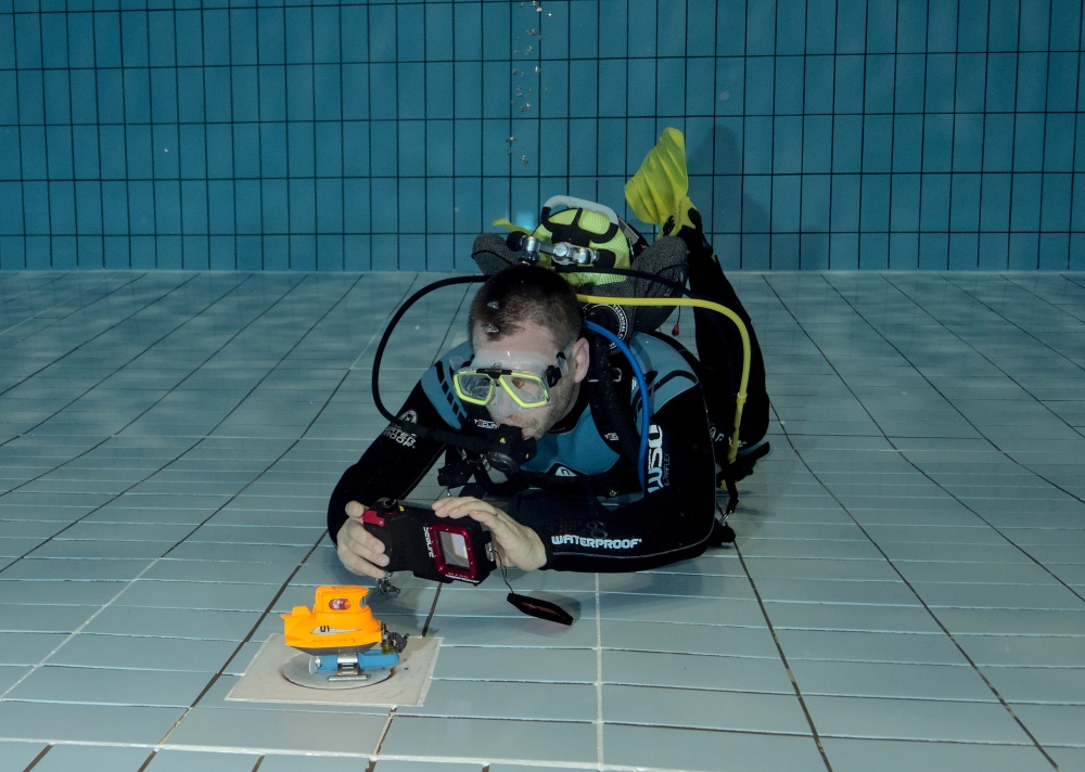 Taucher fotgrafiert ein Spielzeug U-Boot mit einen Handy